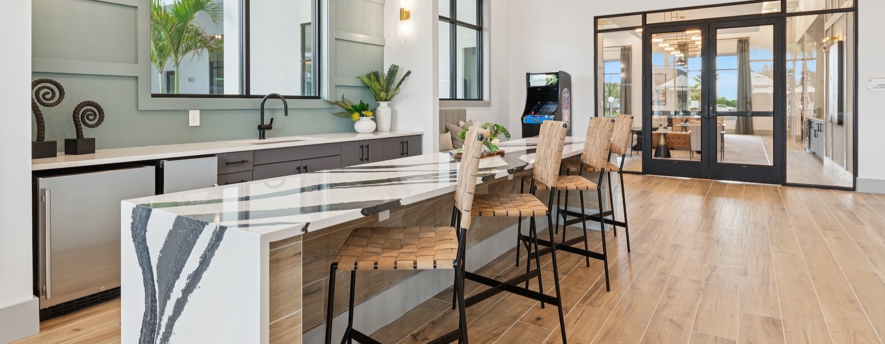 a kitchen with a bar and chairs and large windows